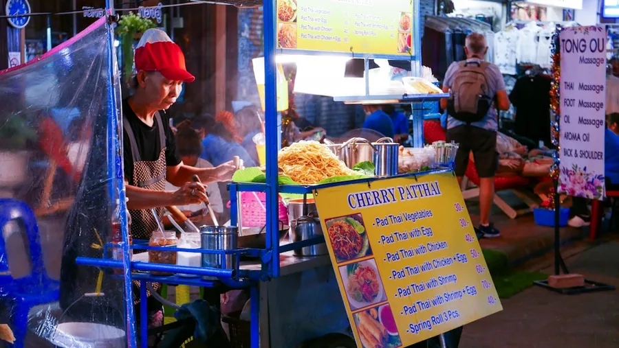 Young couple enjoying pad thai at street stall Bangkok budget meal Thailand
